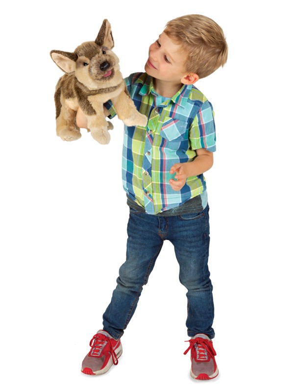 Junge hält Folkmanis Handpuppe Schäferhundwelpe mit braunem Fell und herausgestreckter Zunge in die Höhe