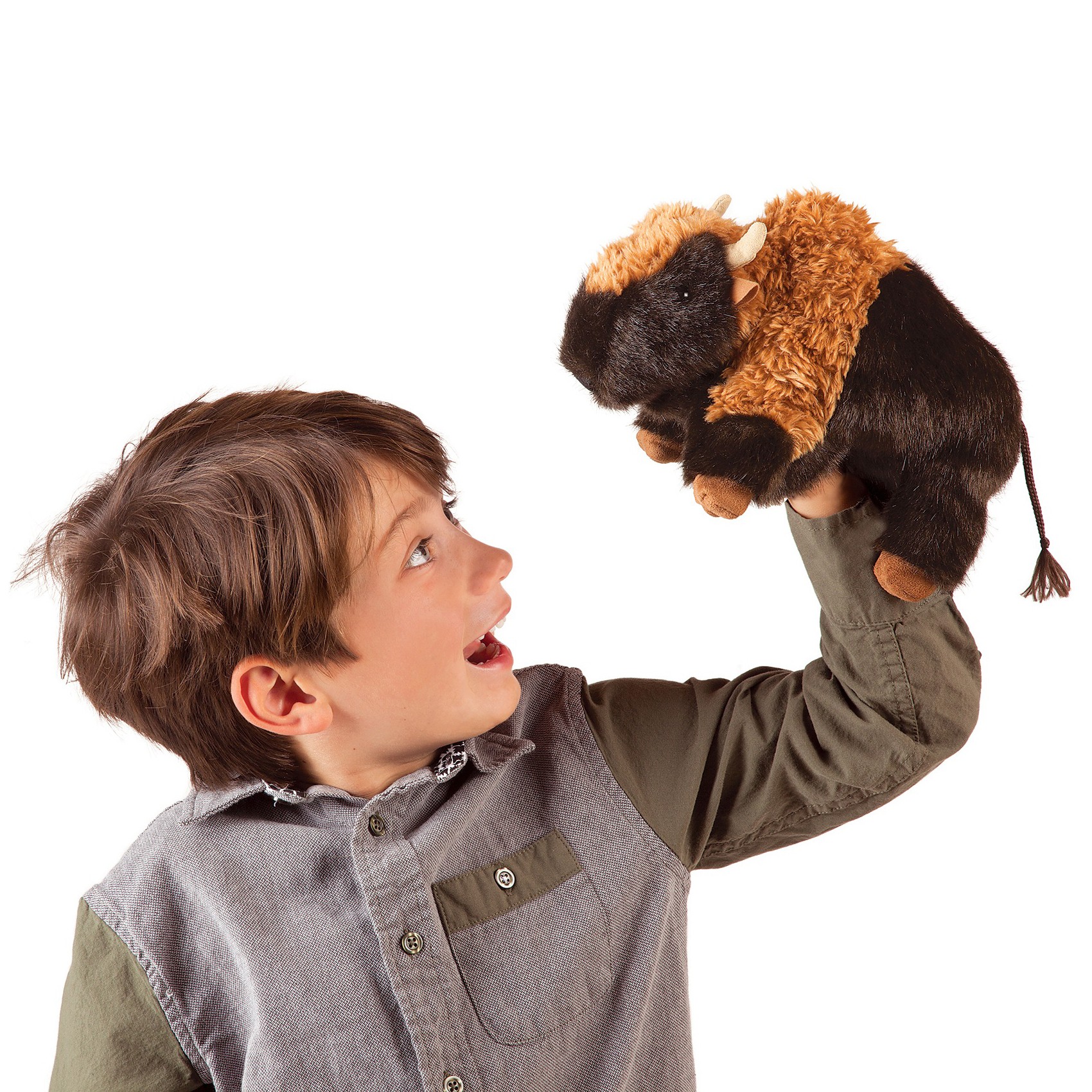 Boy holding a Folkmanis bison hand puppet with dark brown fur and light-coloured horns up in the air while looking at it