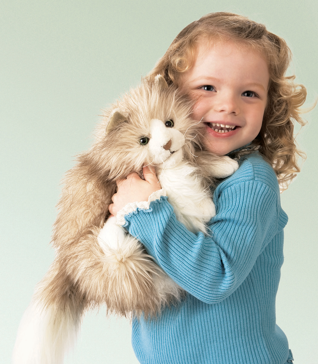 Lachendes Mädchen hält die Folkmanis Handpuppe pummelige Katze mit beigefarbenem Langfell und weißem Bauch im Arm.