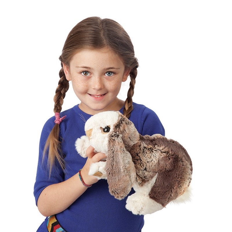 Girl holding a Folkmanis baby lop rabbit hand puppet with brown-and-white fur and long floppy ears towards the camera