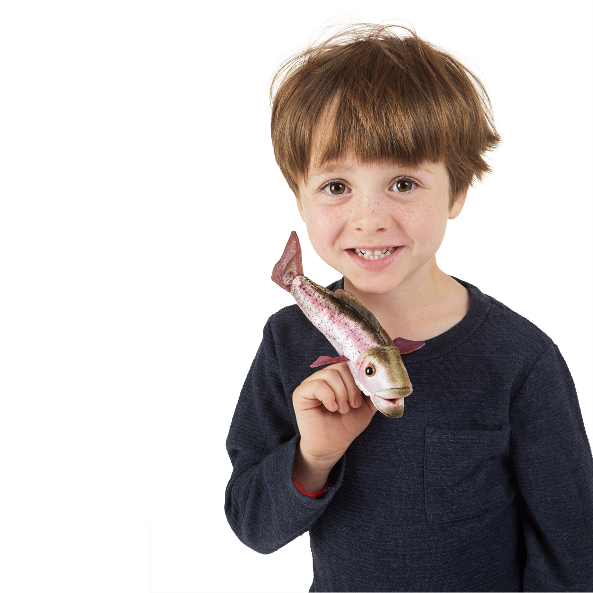 Junge hält Folkmanis Fingerpuppe mini Regenbogenforelle mit geöffnetem Maul auf dem Zeigefinger, rosa-grünes Plüsch-Fischdesign.