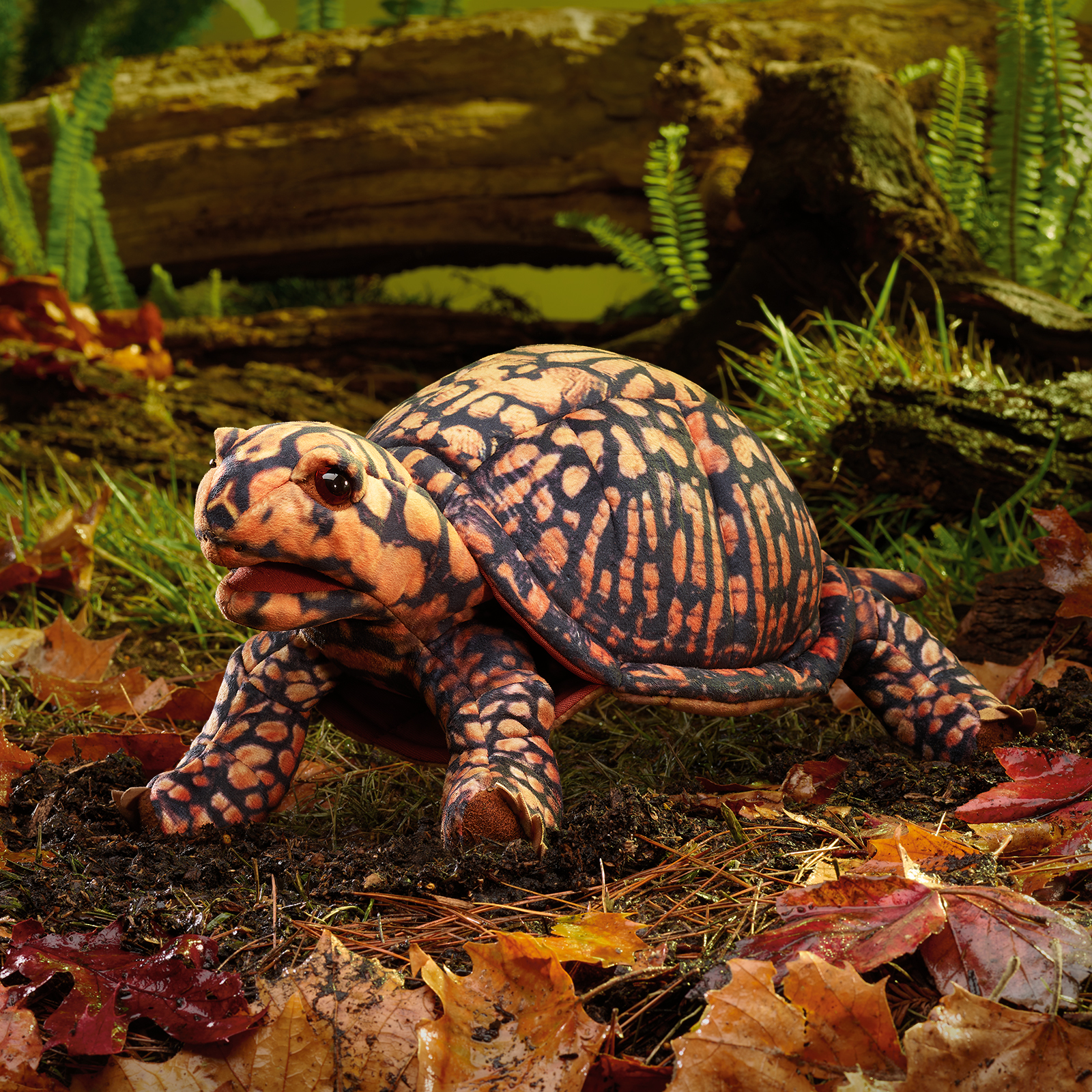 Folkmanis Handpuppe Dosenschildkröte mit orange-schwarzem Schuppenmuster, geöffnetem Maul und detailliertem Panzer, seitliche Ansicht auf Waldboden