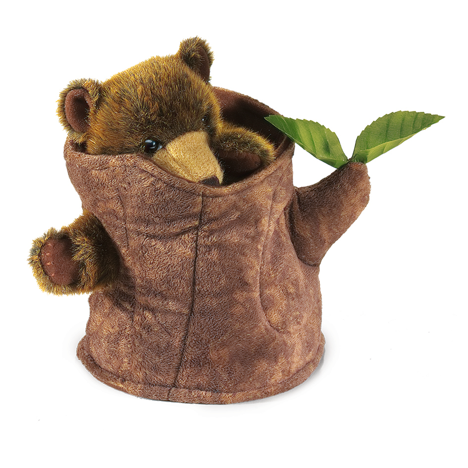 Folkmanis Handpuppe Bär im Baumstumpf aus braunem Plüsch, Bär lugt mit Pfoten und goldenem Schnäuzchen aus dem Stumpf, grüne Blätter seitlich