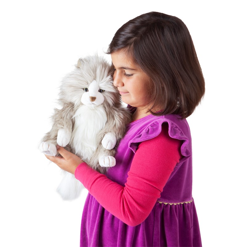 Mädchen hält die Folkmanis Handpuppe flauschige Katze mit grau-weißem Langfell seitlich ans Gesicht geschmiegt.