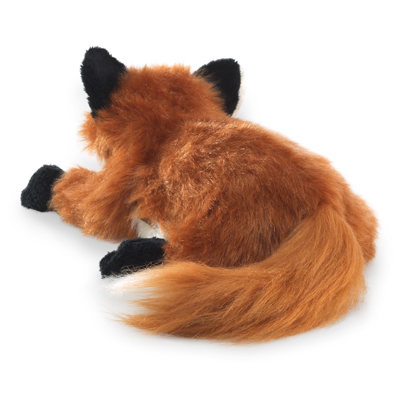 Folkmanis small red fox hand puppet in a curled sleeping pose, reddish-brown long-pile plush with black paws and a bushy tail, angled top view