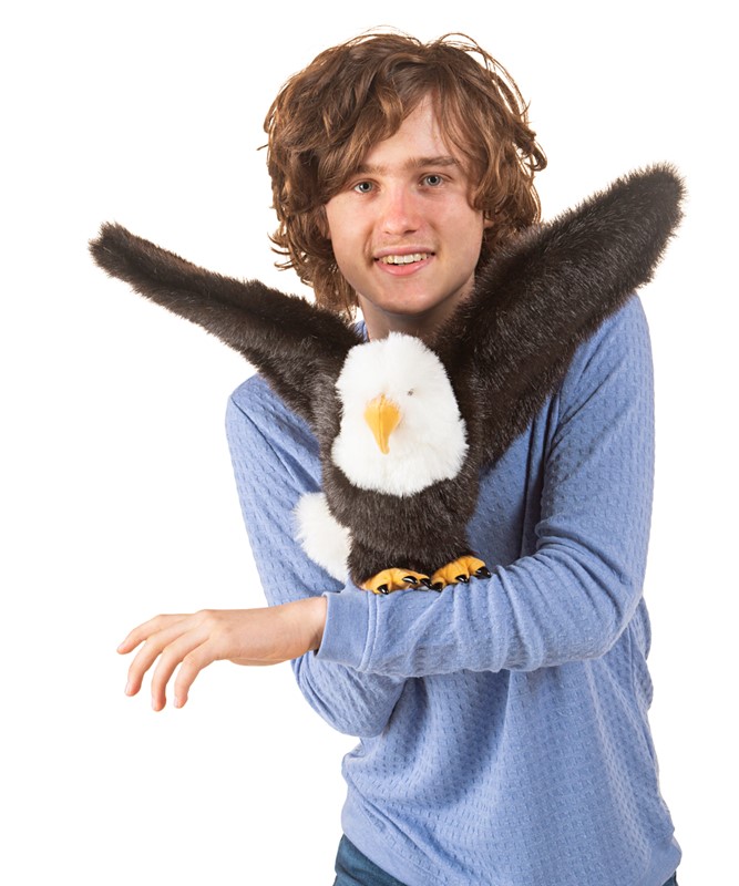Folkmanis bald eagle hand puppet with spread wings, held on the arm of a teenager, front view
