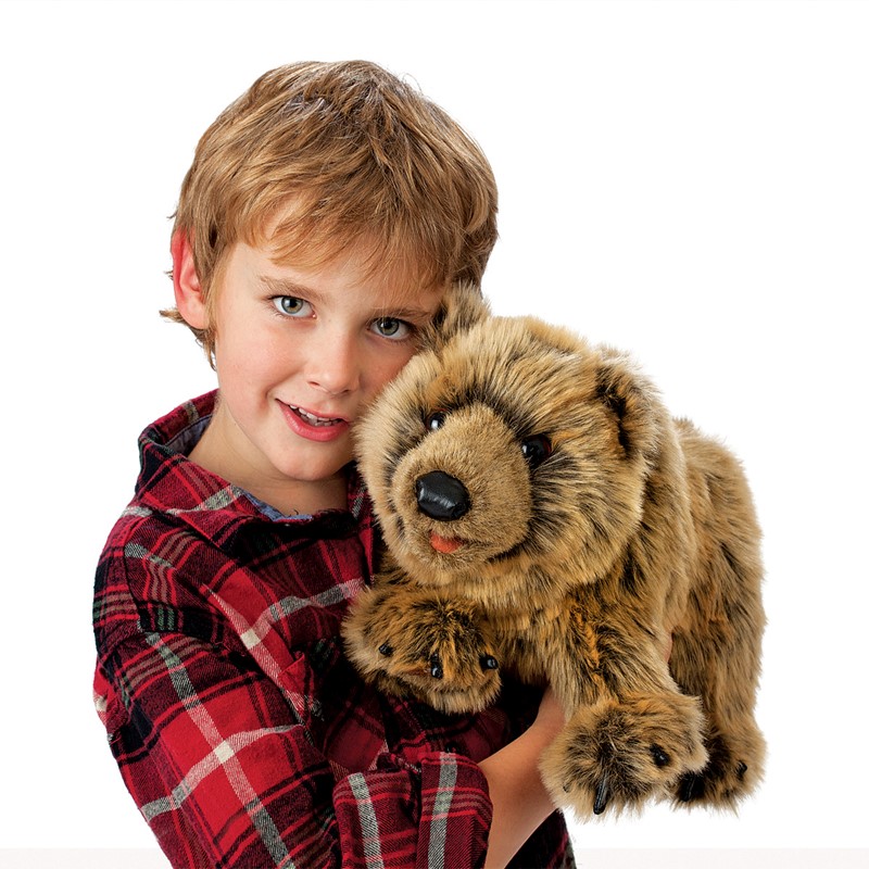 Junge hält Folkmanis Handpuppe Grizzlybär mit braunem Plüschfell und schwarzer Nase in den Armen