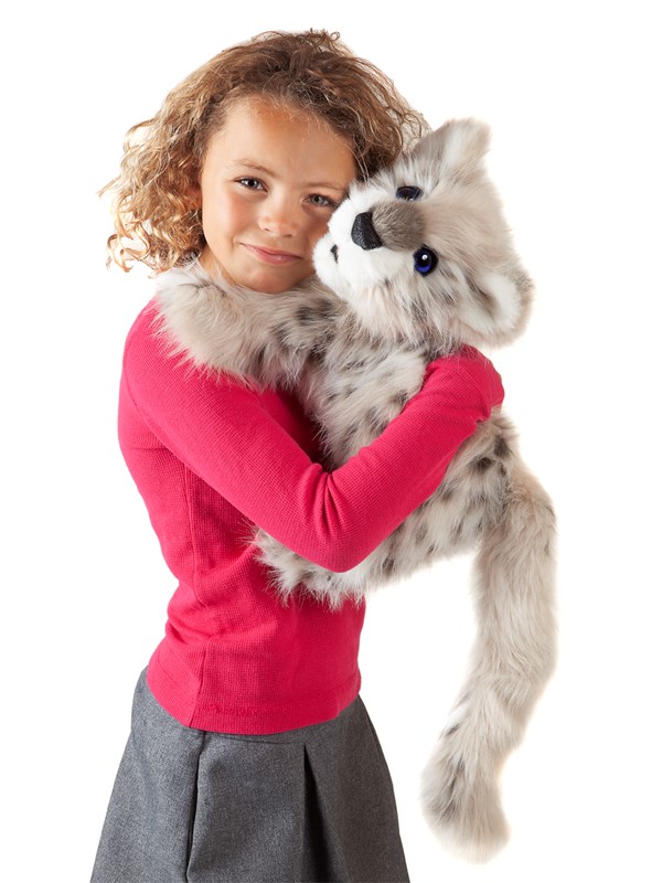 Girl holding the Folkmanis Baby Snow Leopard hand puppet with grey-white fur and dark spots in her arms