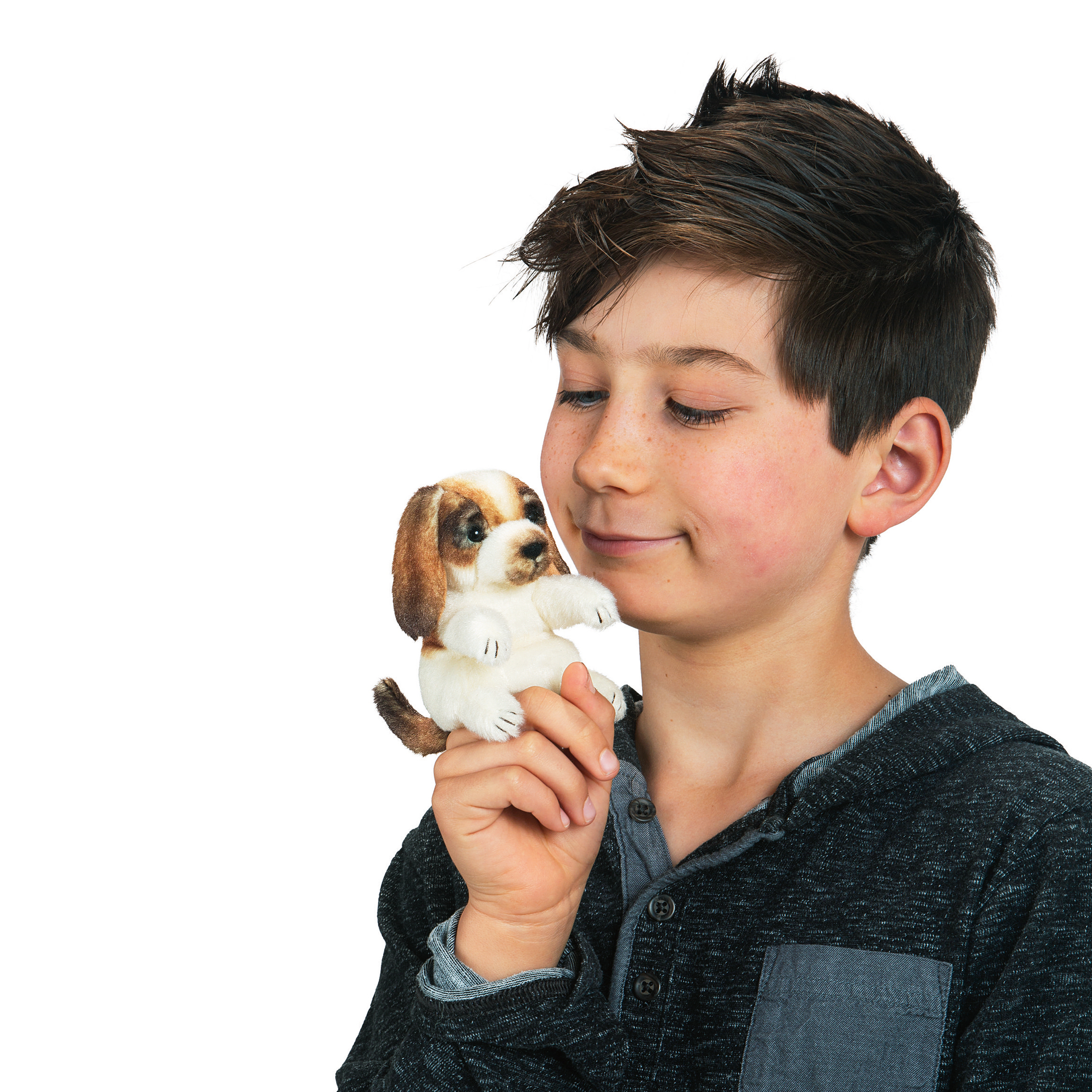 Boy smiling at a small brown-and-white Folkmanis mini dog finger puppet on his finger