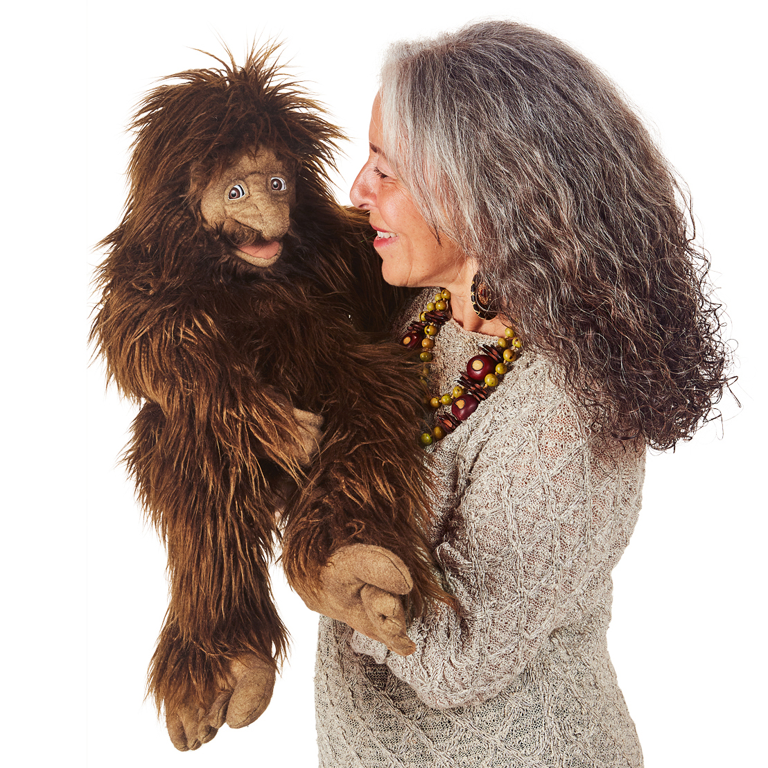 Folkmanis Sasquatch hand puppet with shaggy brown fur, operated by a woman smiling face-to-face with the puppet