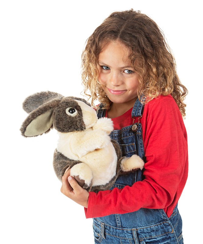 Mädchen hält Folkmanis Handpuppe Holländer-Kaninchen mit grau-weißem Fell und hängenden Ohren in beiden Armen