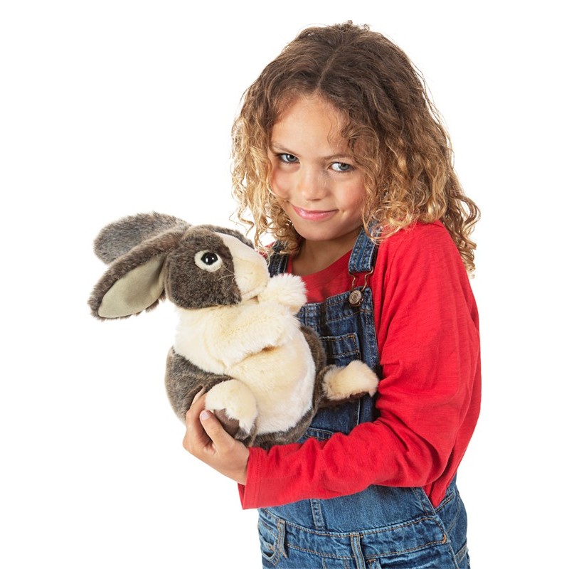 Girl holding a Folkmanis Dutch rabbit hand puppet with grey-and-white fur and floppy ears in both arms