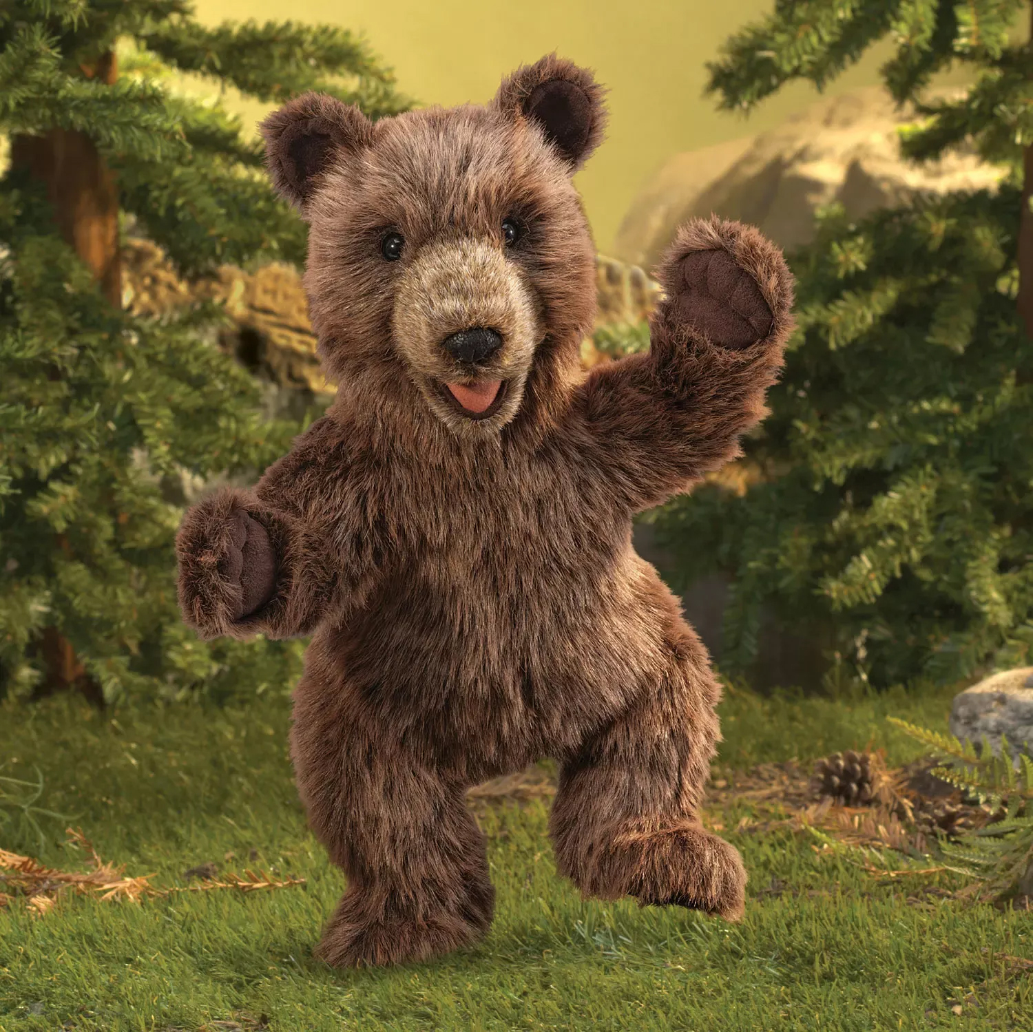 Folkmanis Handpuppe Bärenjunges aus braunem Plüsch, stehend mit geöffnetem Maul und erhobener Pfote, vor Wald-Kulisse