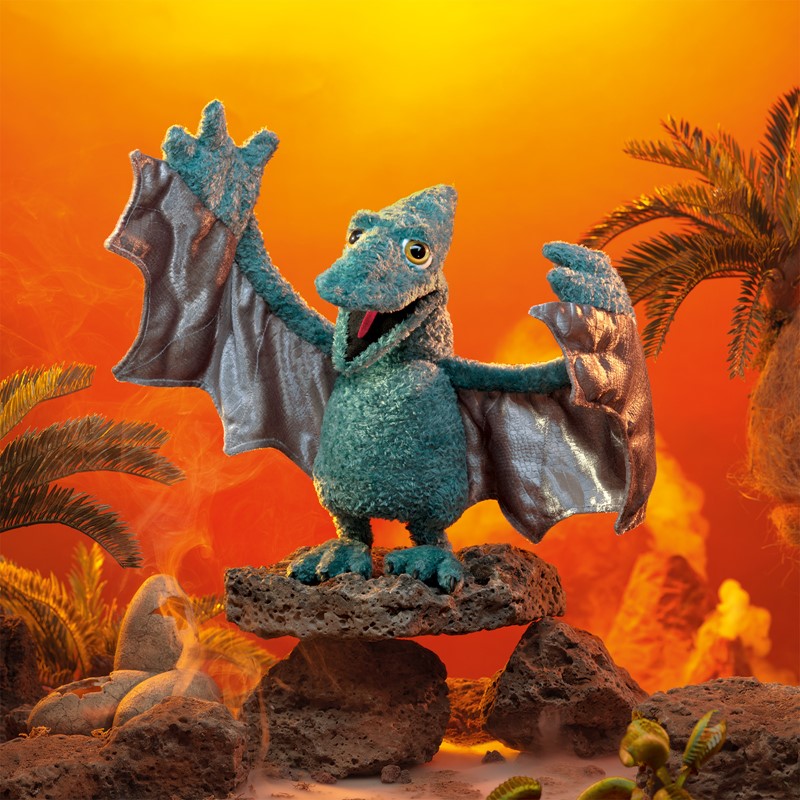 Folkmanis pterodactyl hand puppet in teal with spread wings, standing on lava rock against an orange-red volcano background