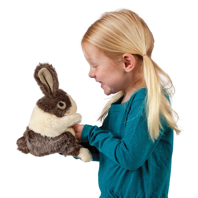 Mädchen führt die Folkmanis Handpuppe Holländer-Kaninchenbaby mit braun-cremefarbenem Fell von unten mit der Hand