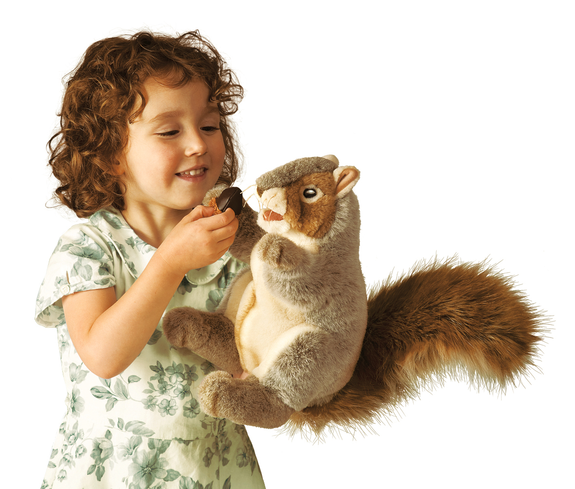 Mädchen hält Folkmanis Handpuppe graues Eichhörnchen mit buschigem Schwanz und hält ihr eine Eichel hin