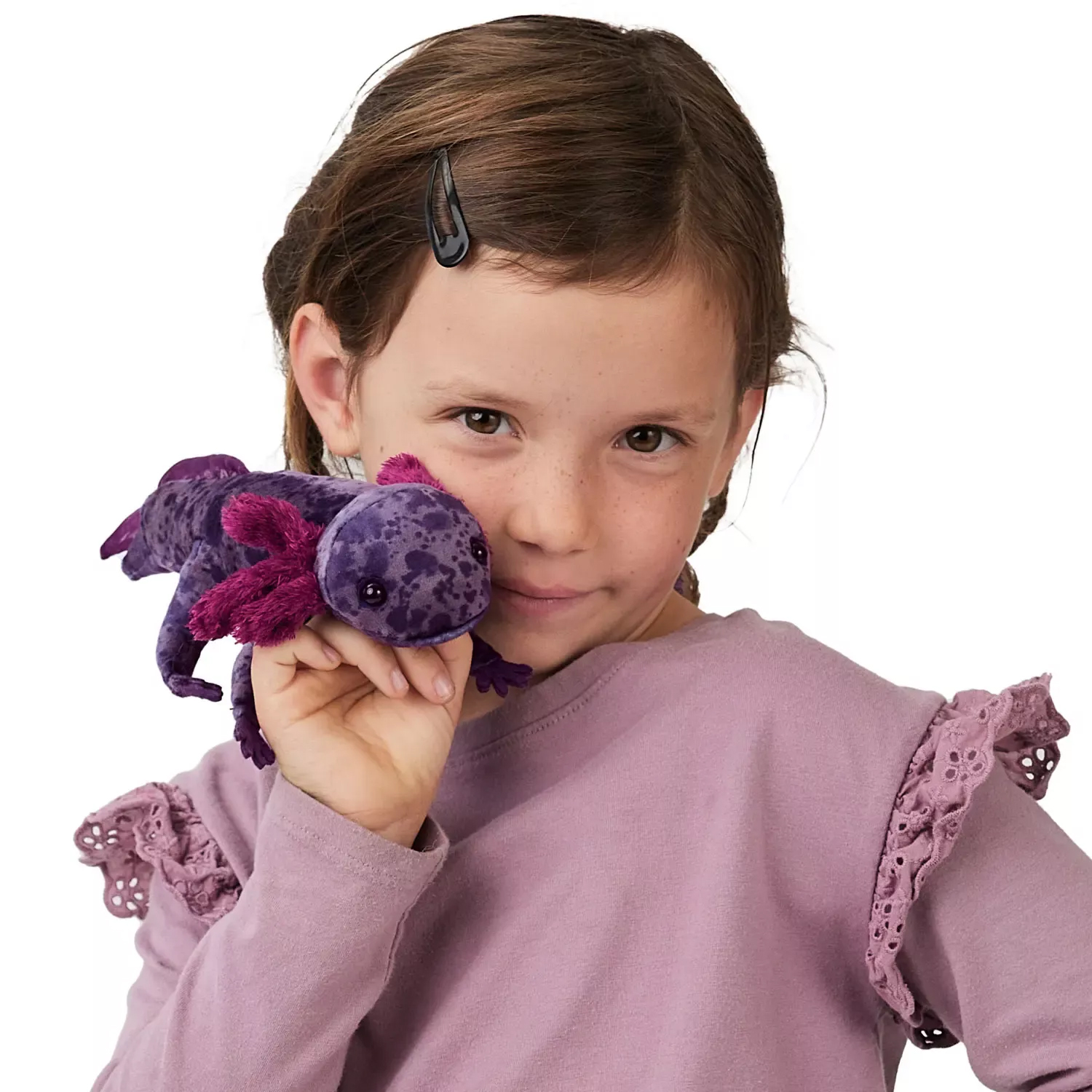 Mädchen hält Folkmanis Fingerpuppe mexikanischer Schwanzlurch in Violett mit pink-lila Kiemen nah ans Gesicht.