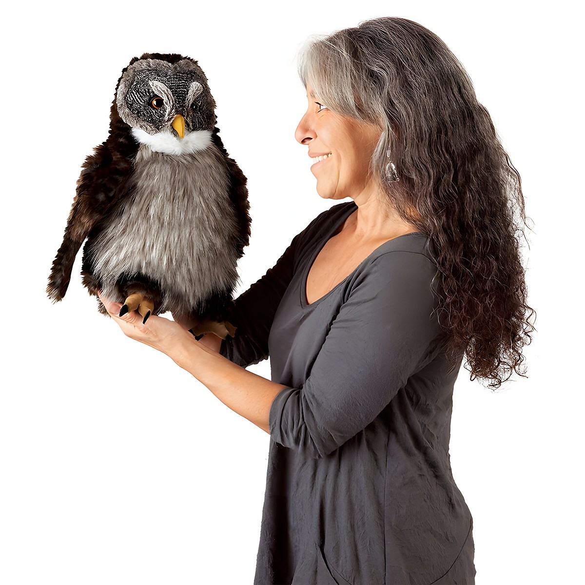 Frau hält Folkmanis Handpuppe Eule mit braunem Gefieder, grauem Bauch und gelbem Schnabel auf der flachen Hand, Seitenansicht.