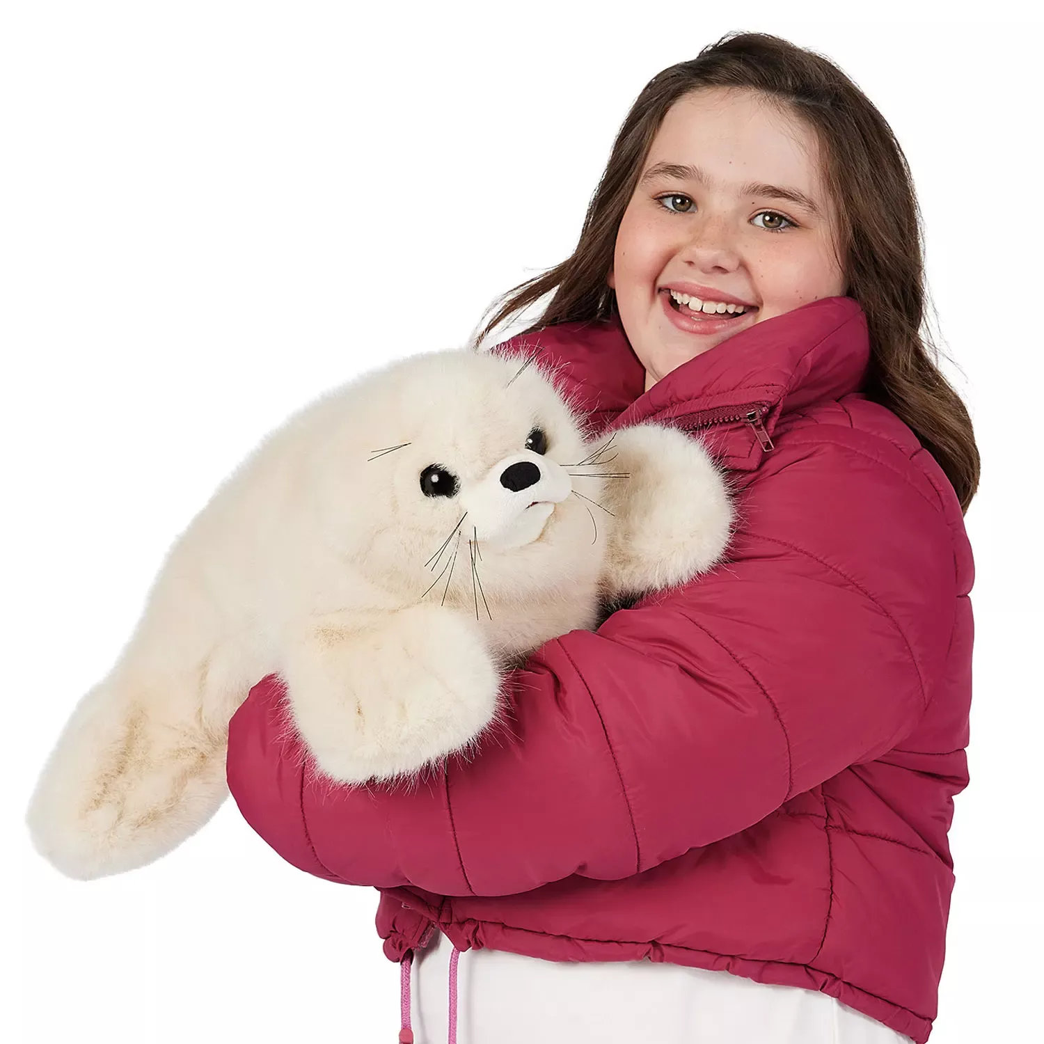 Mädchen in pinkfarbener Jacke hält die Folkmanis Handpuppe Sattelrobben-Baby mit weißem Plüschfell und schwarzen Knopfaugen im Arm.
