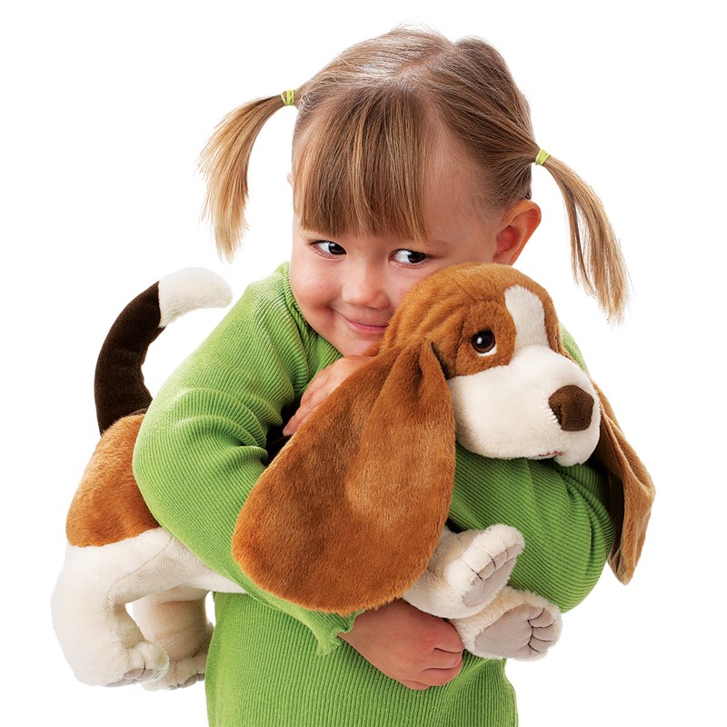 Young girl hugging the Folkmanis Basset Hound hand puppet with long floppy ears and brown-and-white fur