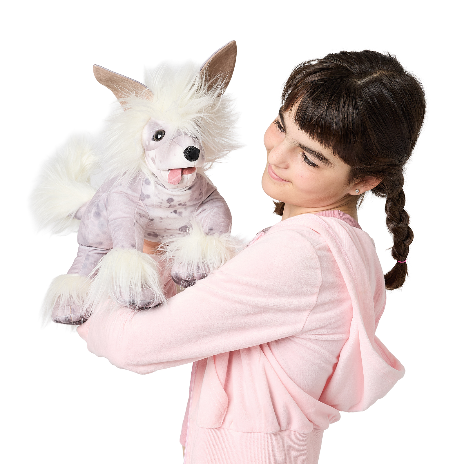 Mädchen hält Folkmanis Handpuppe Chinesischer Schopfhund mit weißem Fellschopf, geflecktem Körper und herausgestreckter Zunge in die Höhe