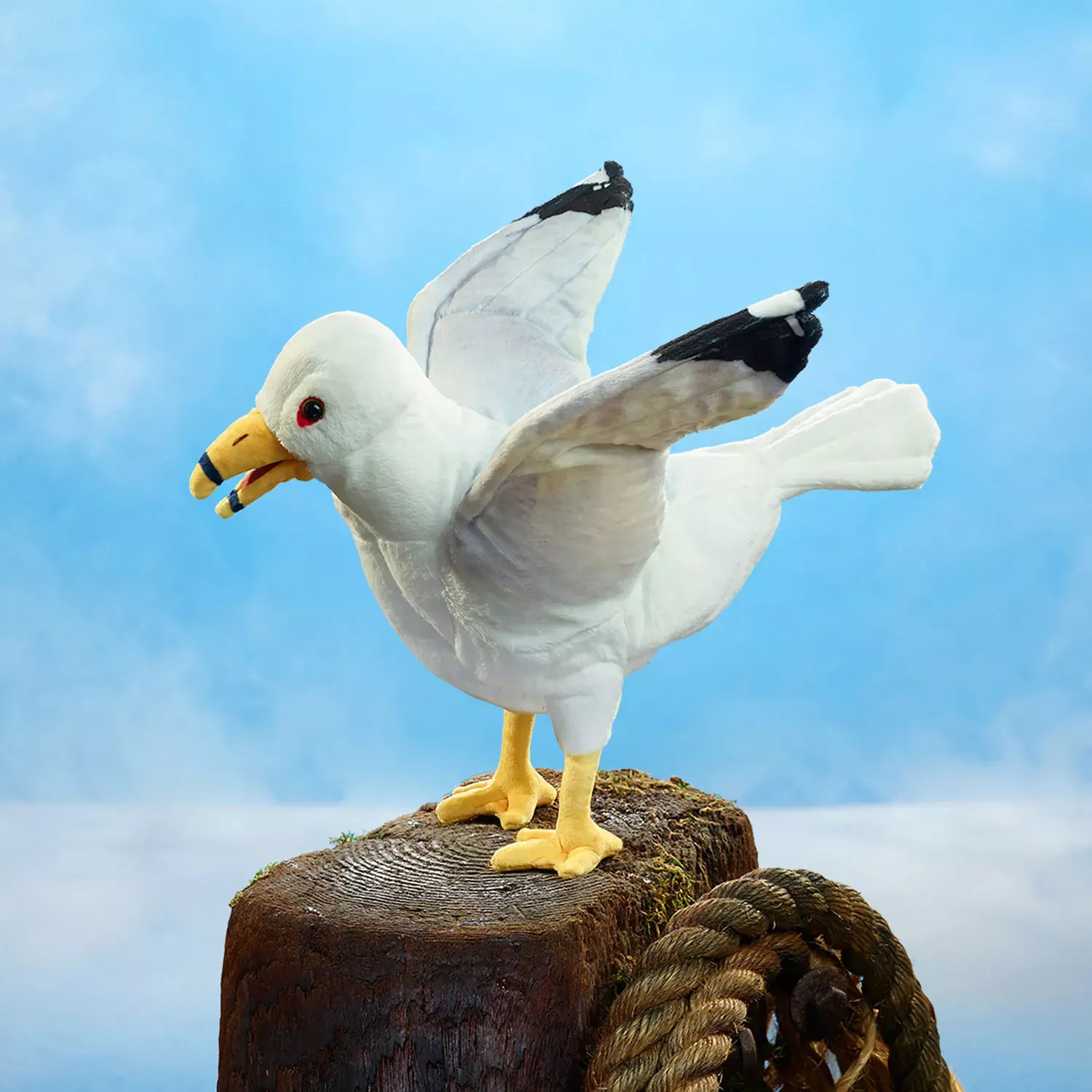 Folkmanis seagull hand puppet with spread wings, white plumage, black wingtips and a yellow beak, perched on a wooden post