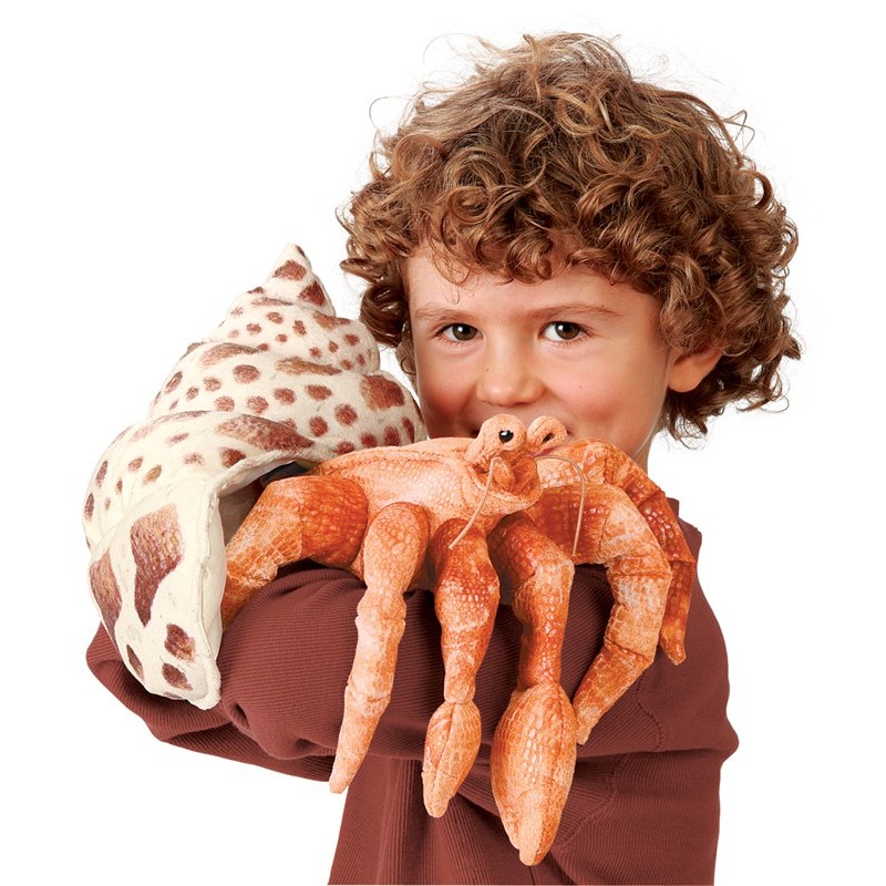 Folkmanis Handpuppe Einsiedlerkrebs in Orange mit geflecktem Schneckenhaus, von einem Kind in die Kamera gehalten