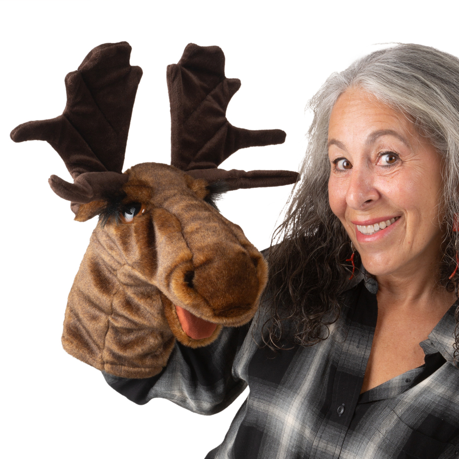 Folkmanis Elch-Handpuppe mit großem Geweih, braunem Plüschfell und beweglichem Maul, von einer Frau auf der Hand getragen.
