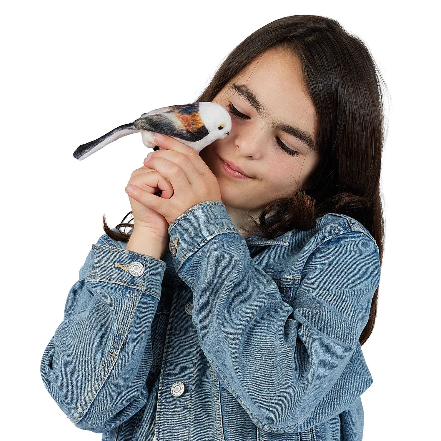 Mädchen hält Folkmanis Fingerpuppe mini Schwanzmeise mit weißem Kopf und rostbraunem Gefieder nah ans Gesicht, Augen geschlossen