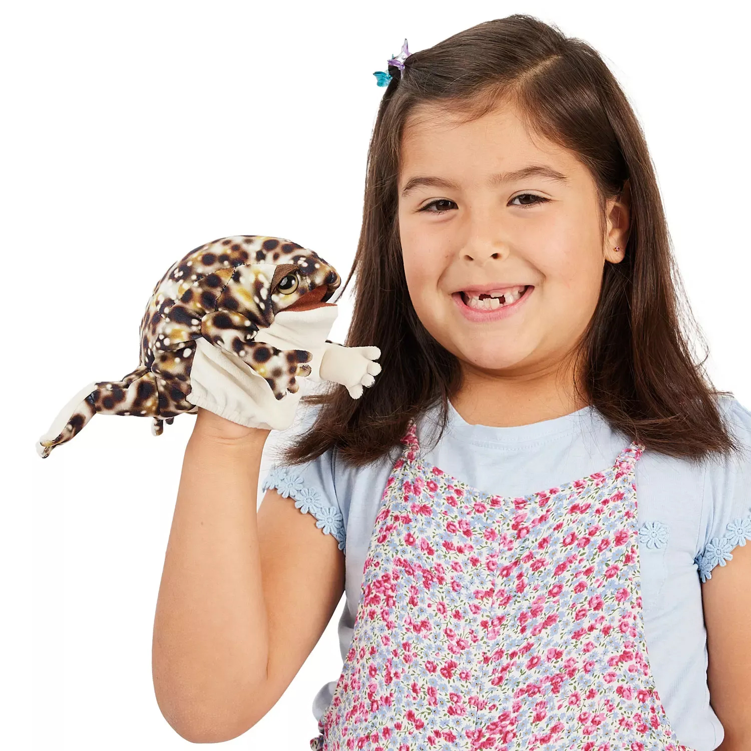 Girl holding a Folkmanis desert rain frog hand puppet with a brown spotted pattern and light-coloured belly up to the camera