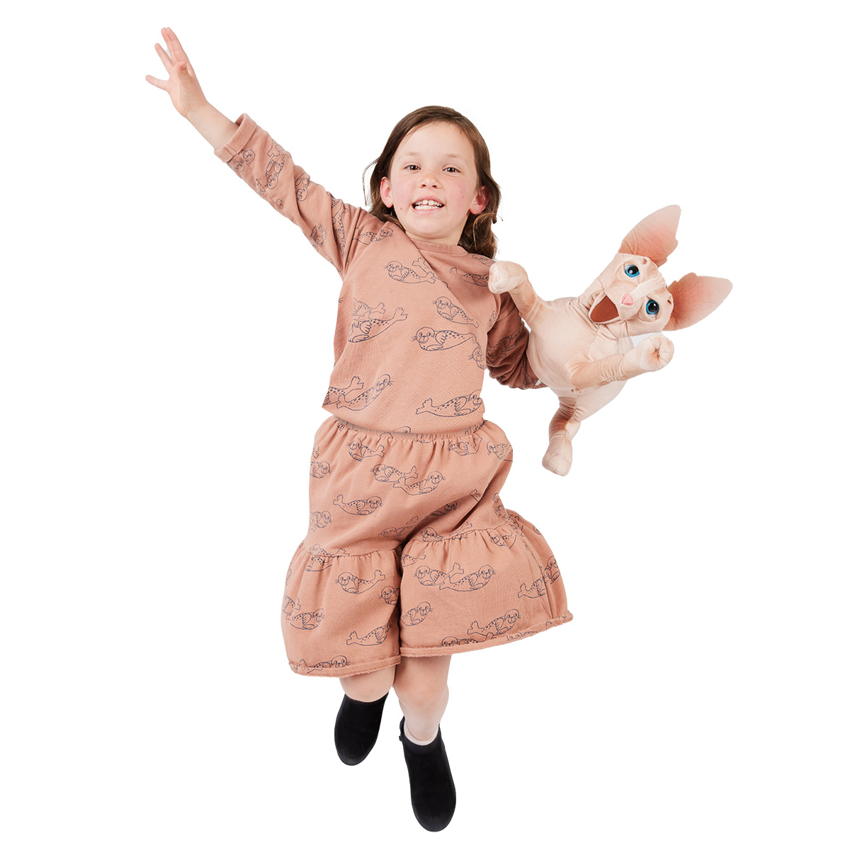 Mädchen springt freudig und hält eine Folkmanis Handpuppe Sphinx Katze mit großen Ohren und blauen Augen in die Höhe.