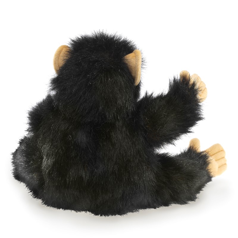 Folkmanis baby chimpanzee hand puppet seen from behind: black plush fur, beige ears and palms, one paw raised