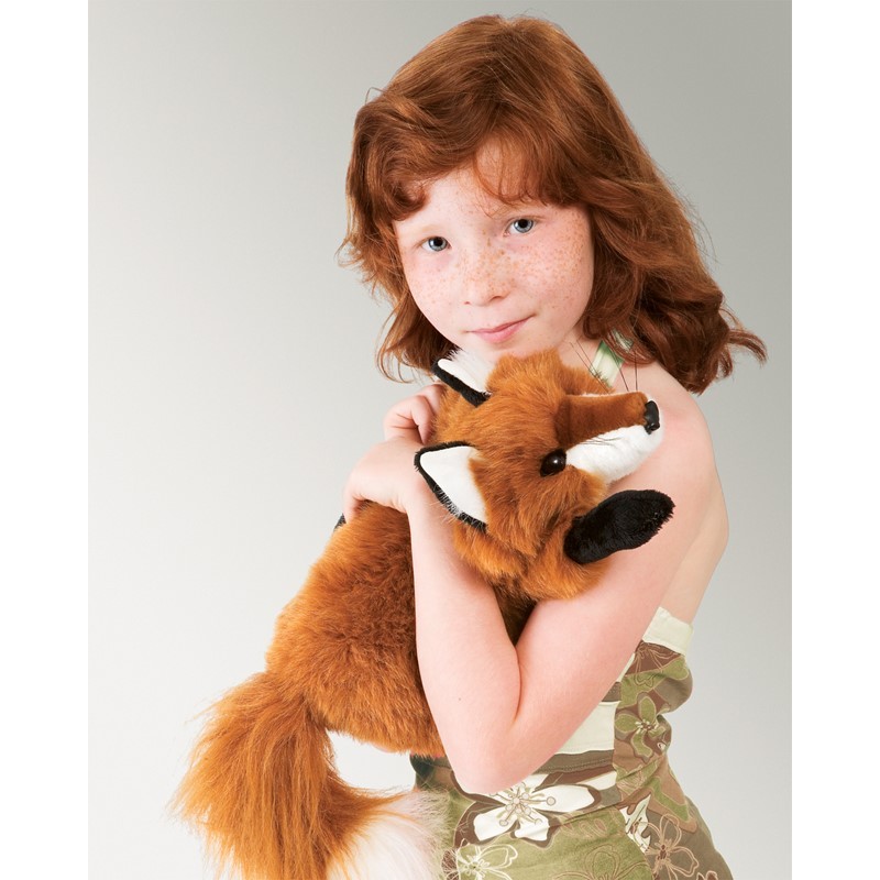 Mädchen hält die Folkmanis Handpuppe kleiner Rotfuchs mit rotbraunem Fell, weißer Brust und schwarzen Pfoten im Arm.
