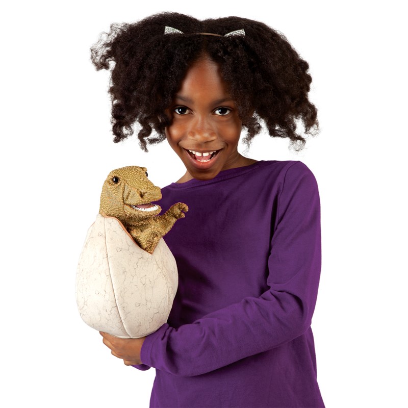 Girl holding the Folkmanis hand puppet baby dinosaur in egg, brown-green dinosaur peeking out of a cream-coloured egg
