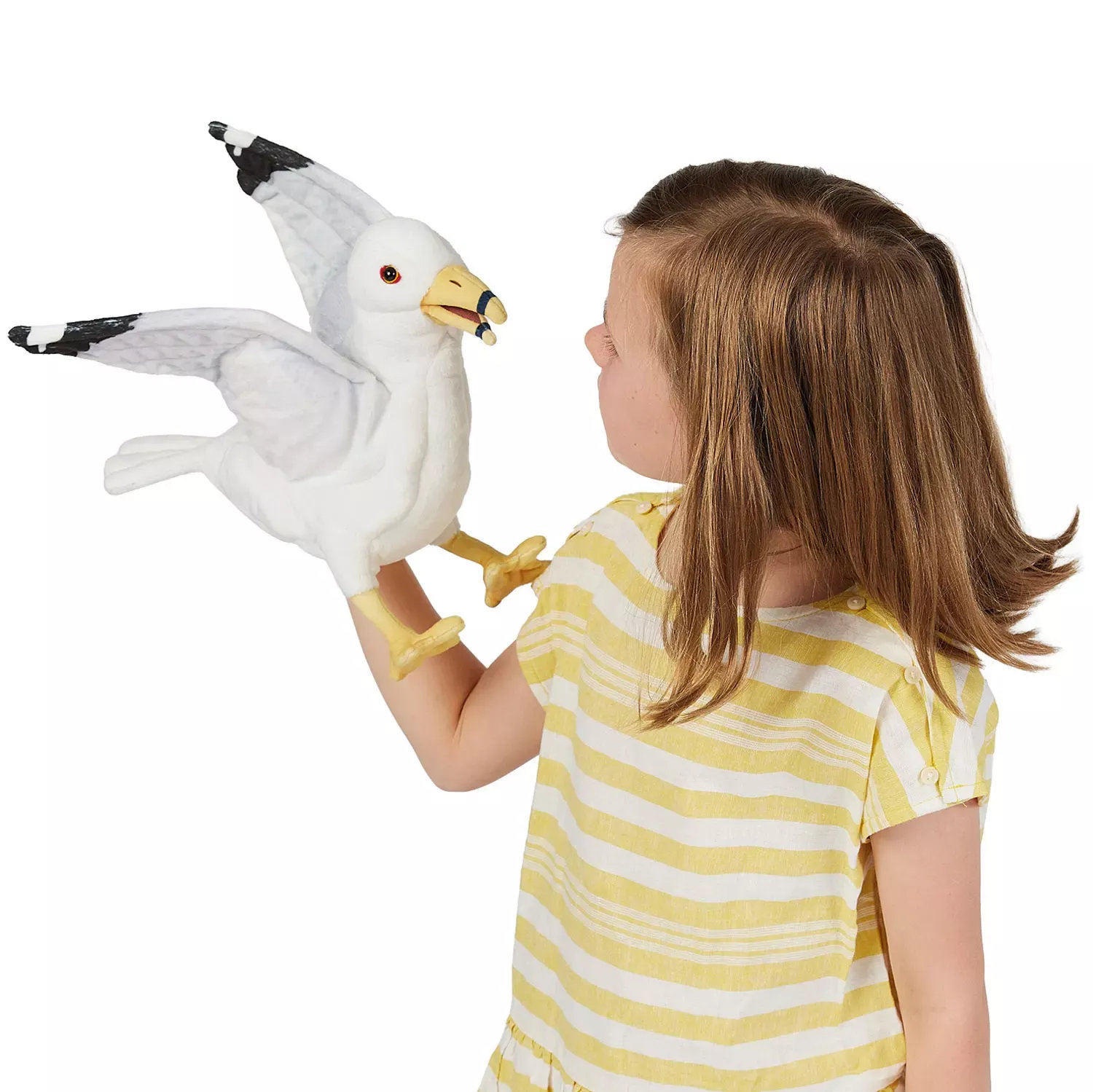 Girl holding a Folkmanis seagull hand puppet with spread wings, white plumage and black-grey wingtips on her hand
