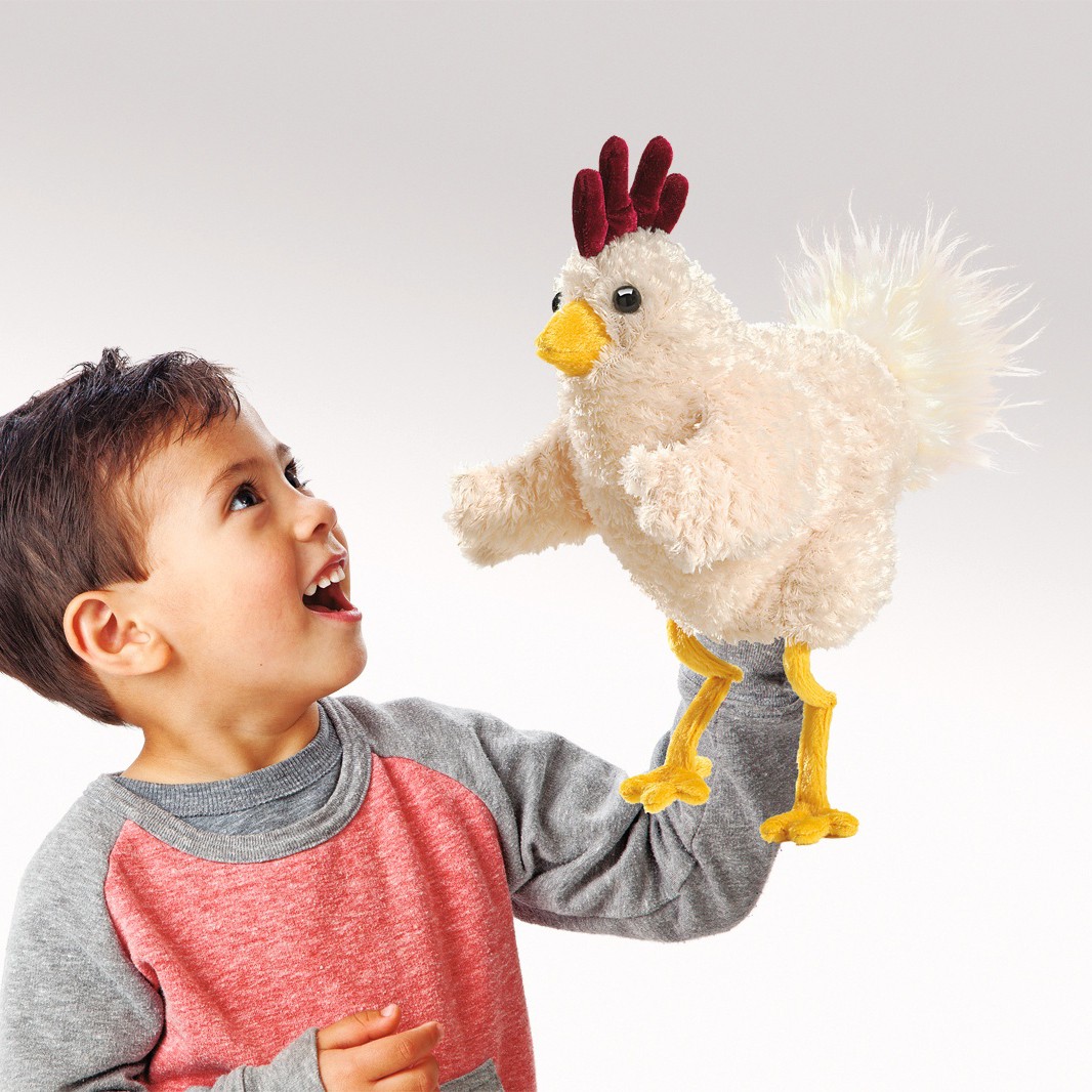 Junge führt die Folkmanis Handpuppe Lustiges Huhn mit weißem Plüsch, dunkelrotem Kamm und gelben Beinen an seiner Hand.