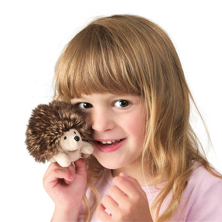 Mädchen hält winzige Folkmanis Fingerpuppe Mini-Igel mit braunem Stachelrücken und hellem Bauch nah ans Gesicht