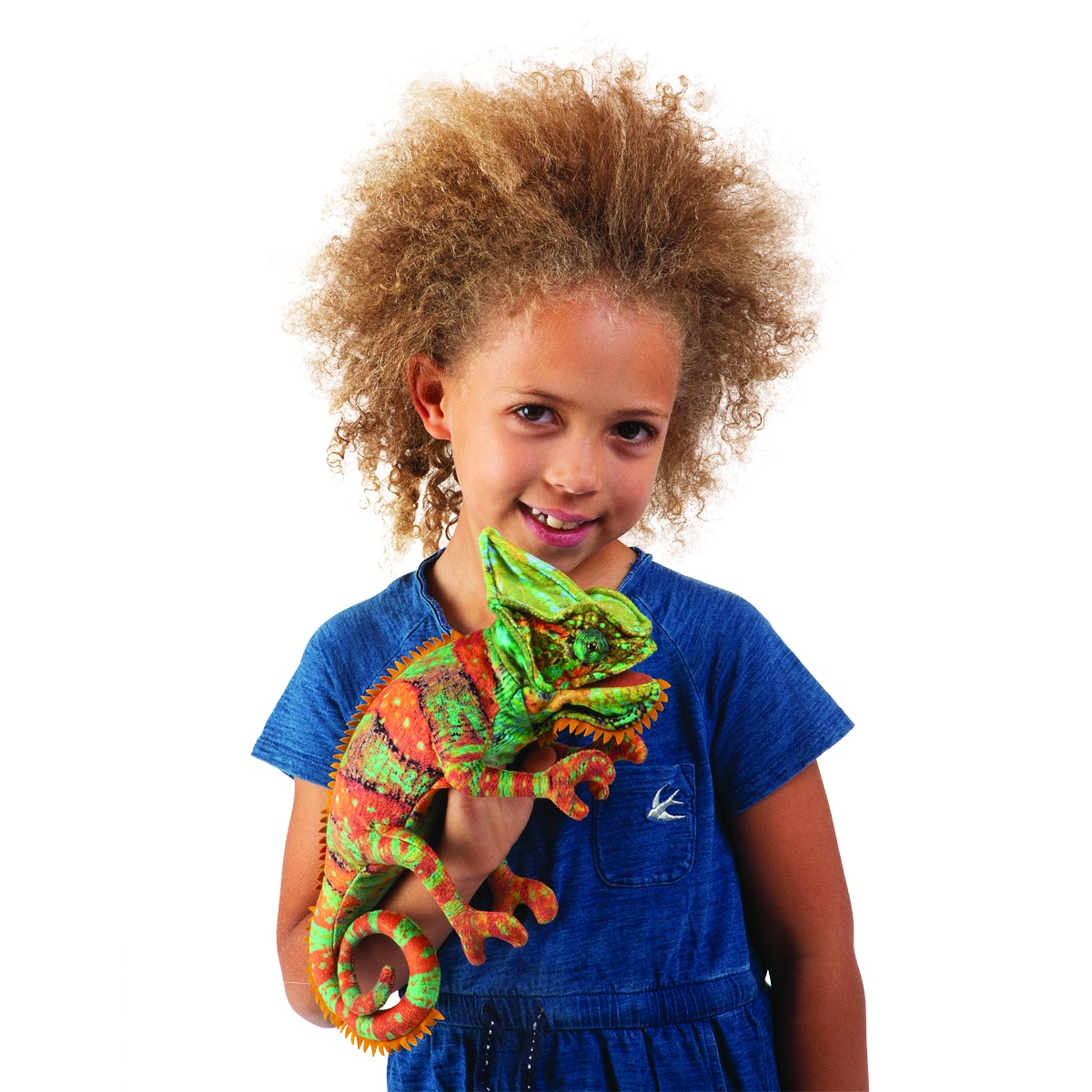 Mädchen hält Folkmanis Handpuppe kleines Chamäleon in Grün-Orange mit strukturiertem Schuppenmuster seitlich in die Kamera.