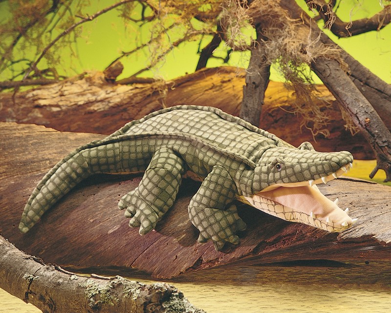 Folkmanis Handpuppe Alligator mit geöffnetem Maul und detaillierter grüner Schuppentextur, auf einem Baumstamm liegend