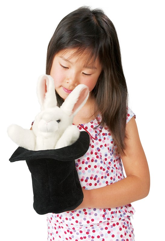 Girl holding a Folkmanis hand puppet of a white rabbit in a black top hat, smiling as she looks down at it