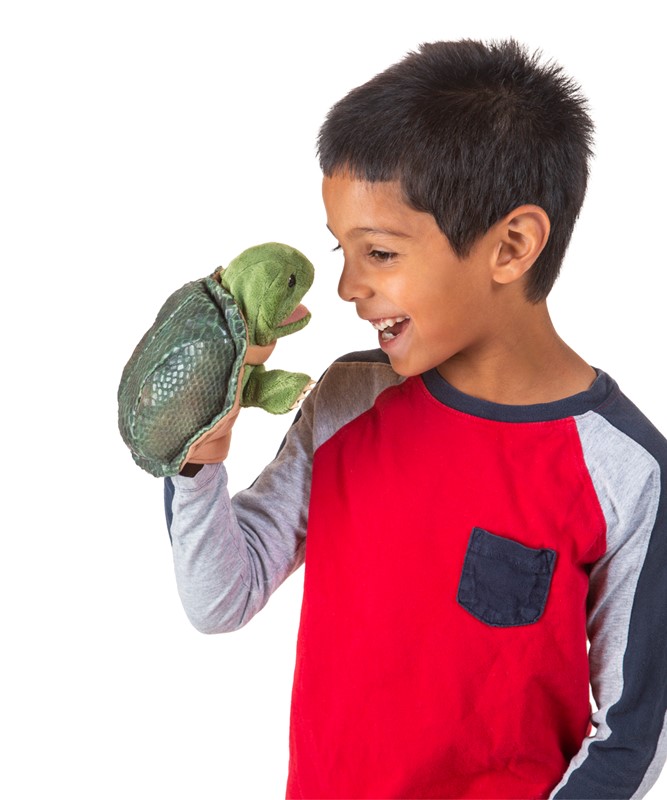 Junge hält Folkmanis Handpuppe kleine Schildkröte mit geöffnetem Maul auf der Hand und lacht sie an