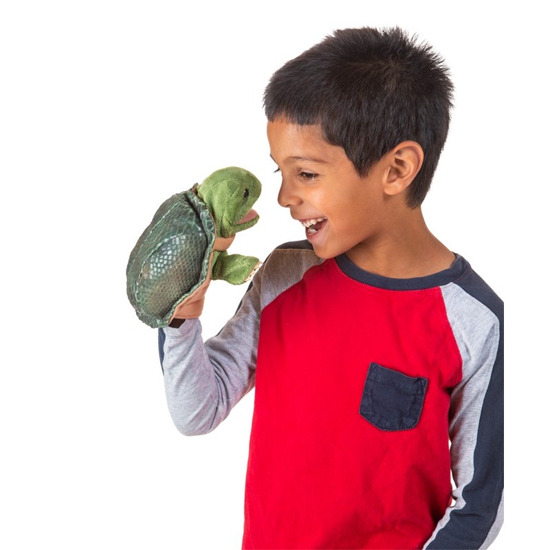 Boy holding the Folkmanis little turtle hand puppet with open mouth on his hand, laughing at it