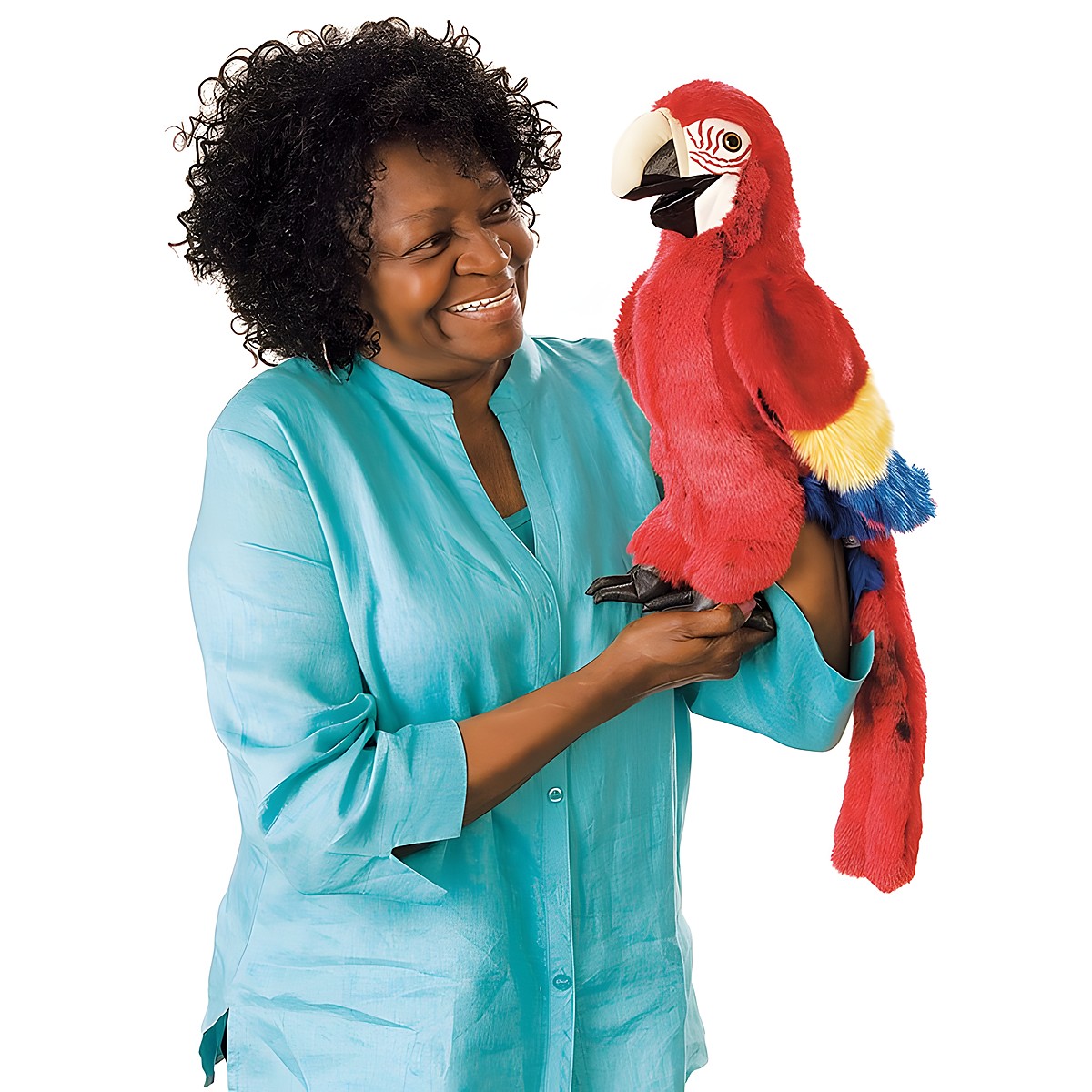 Folkmanis Handpuppe Ara in leuchtendem Rot mit gelb-blauen Flügeln, von einer lächelnden Frau auf dem Arm getragen
