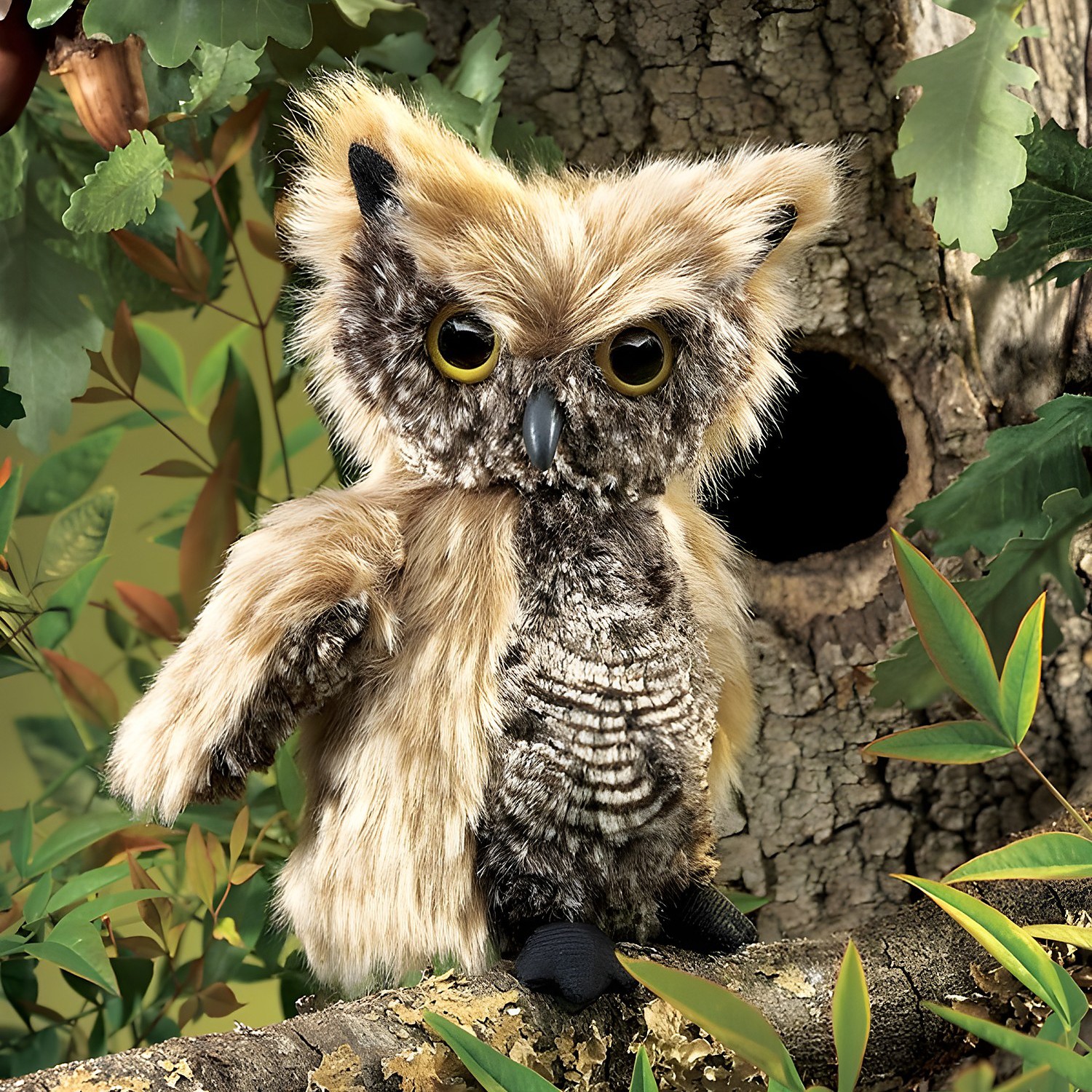 Folkmanis Handpuppe Kreischeule mit beige-braunem Gefieder und gelben Augen, auf einem Ast vor Baumhöhle sitzend