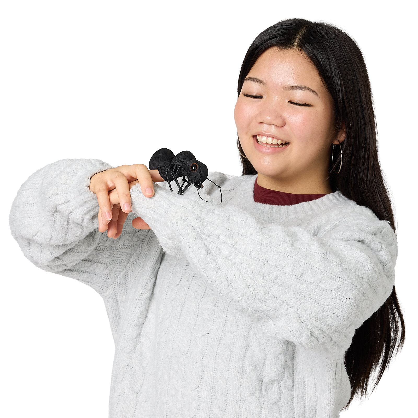 Folkmanis mini ant finger puppet in black on the index finger of a smiling young woman in a knit sweater
