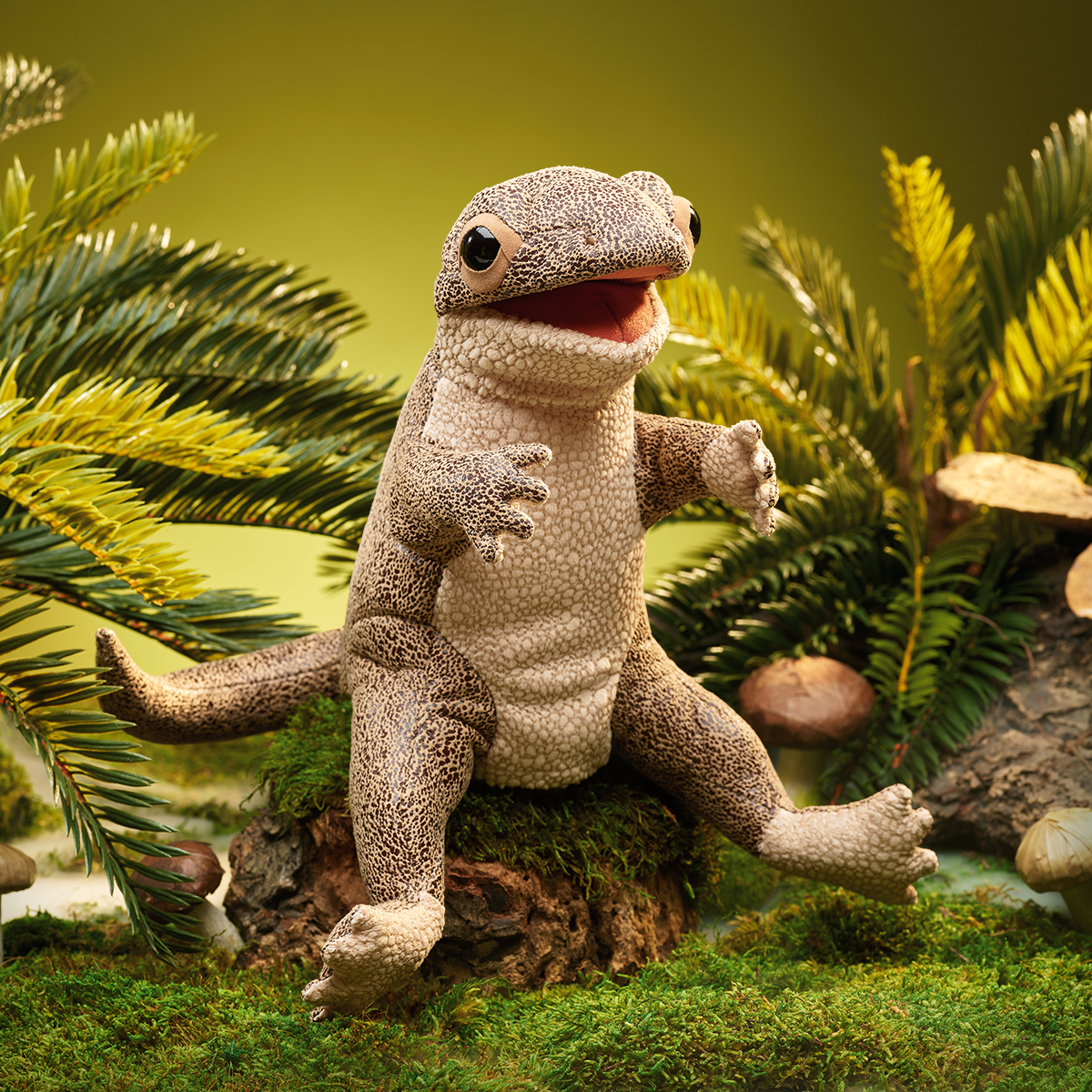 Folkmanis lizard hand puppet with detailed scale texture, open mouth and black eyes, sitting on a tree stump