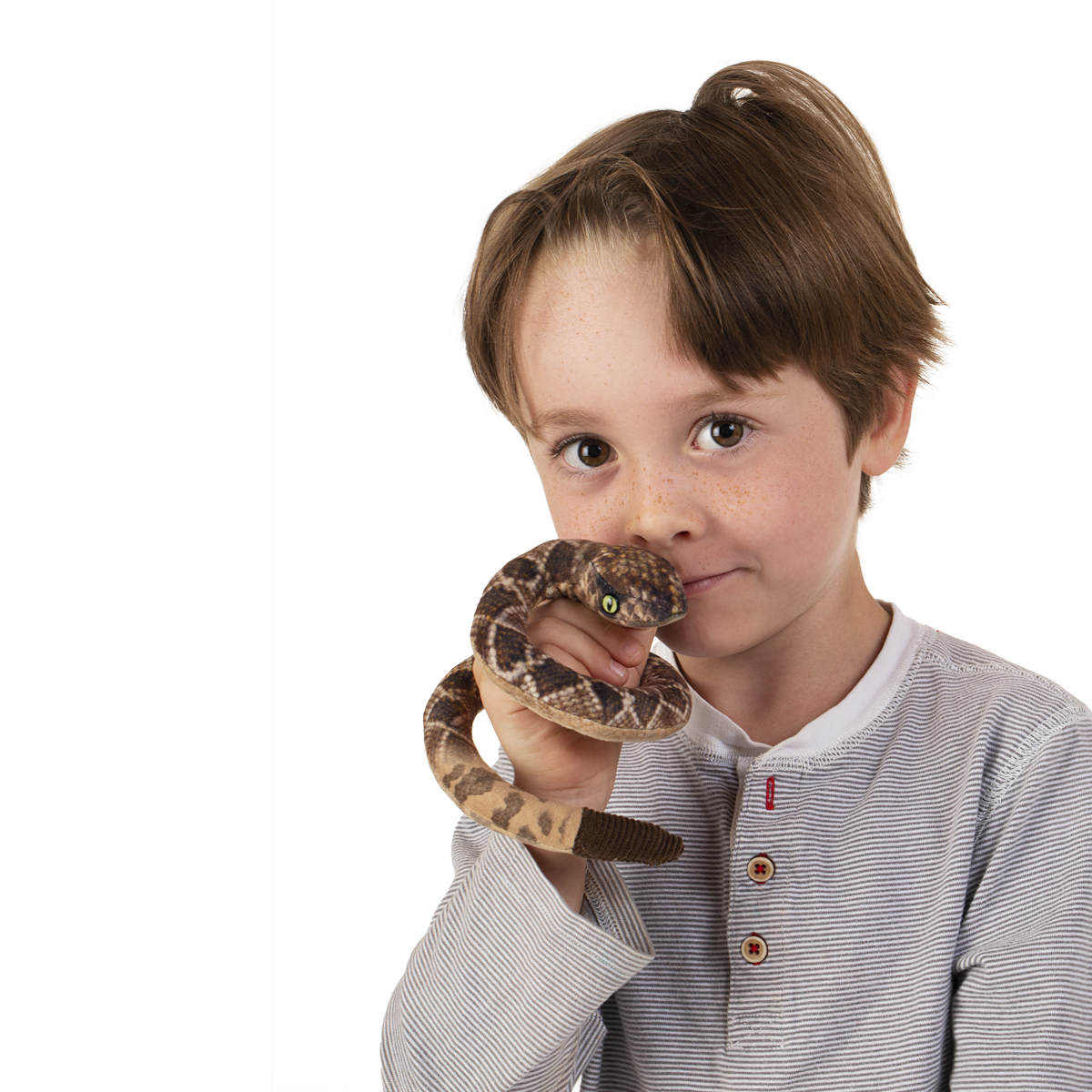 Junge hält Folkmanis Fingerpuppe mini Klapperschlange mit braun-beigem Schuppenmuster auf den Fingern, Kopf nah ans Gesicht gehalten.