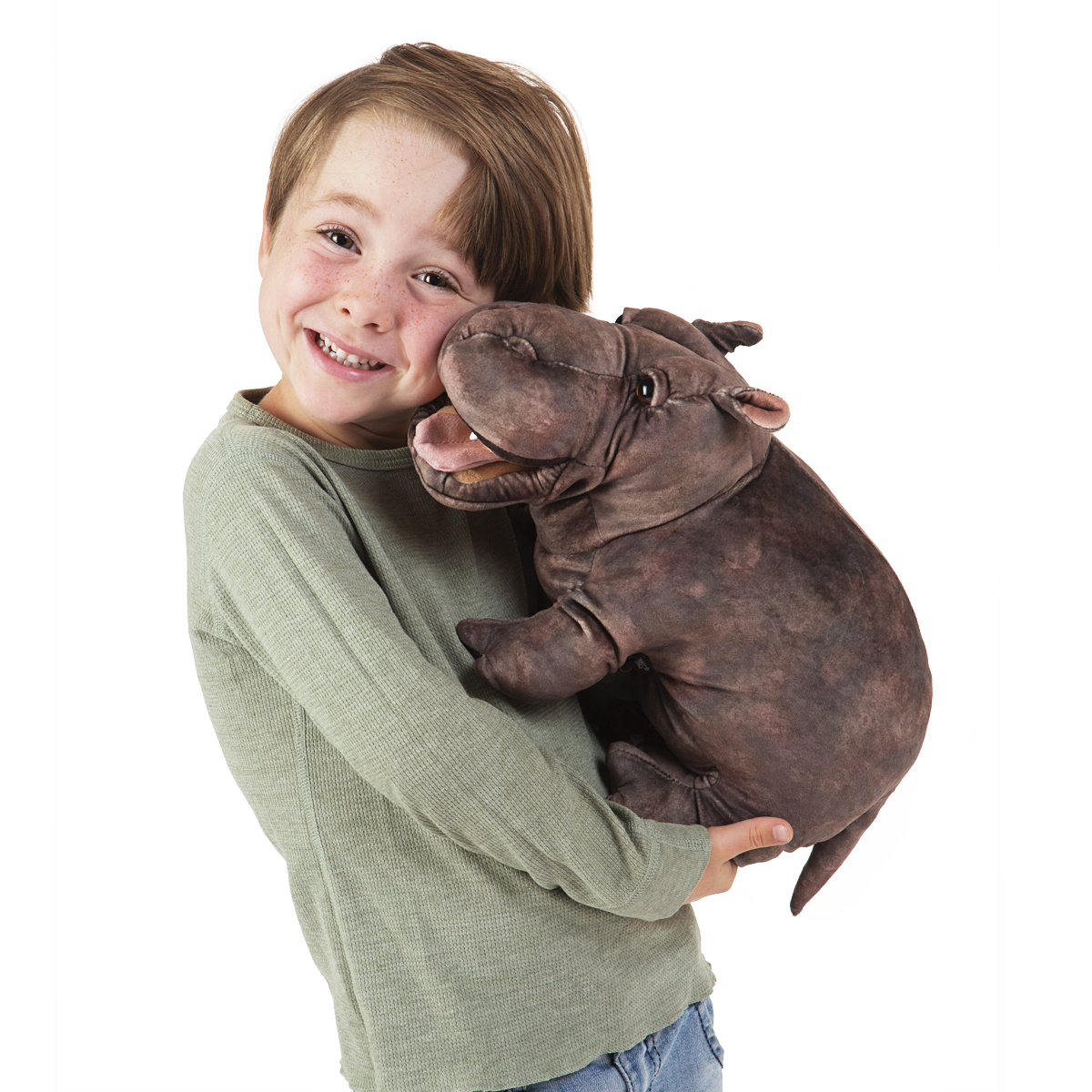 Smiling boy hugging the Folkmanis baby hippo hand puppet with open mouth in dark brown plush