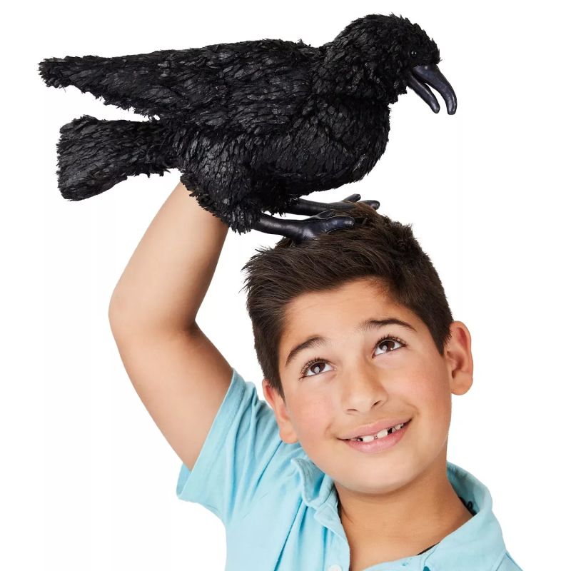 Junge spielt mit der Folkmanis-Handpuppe Krähe auf der erhobenen Hand
